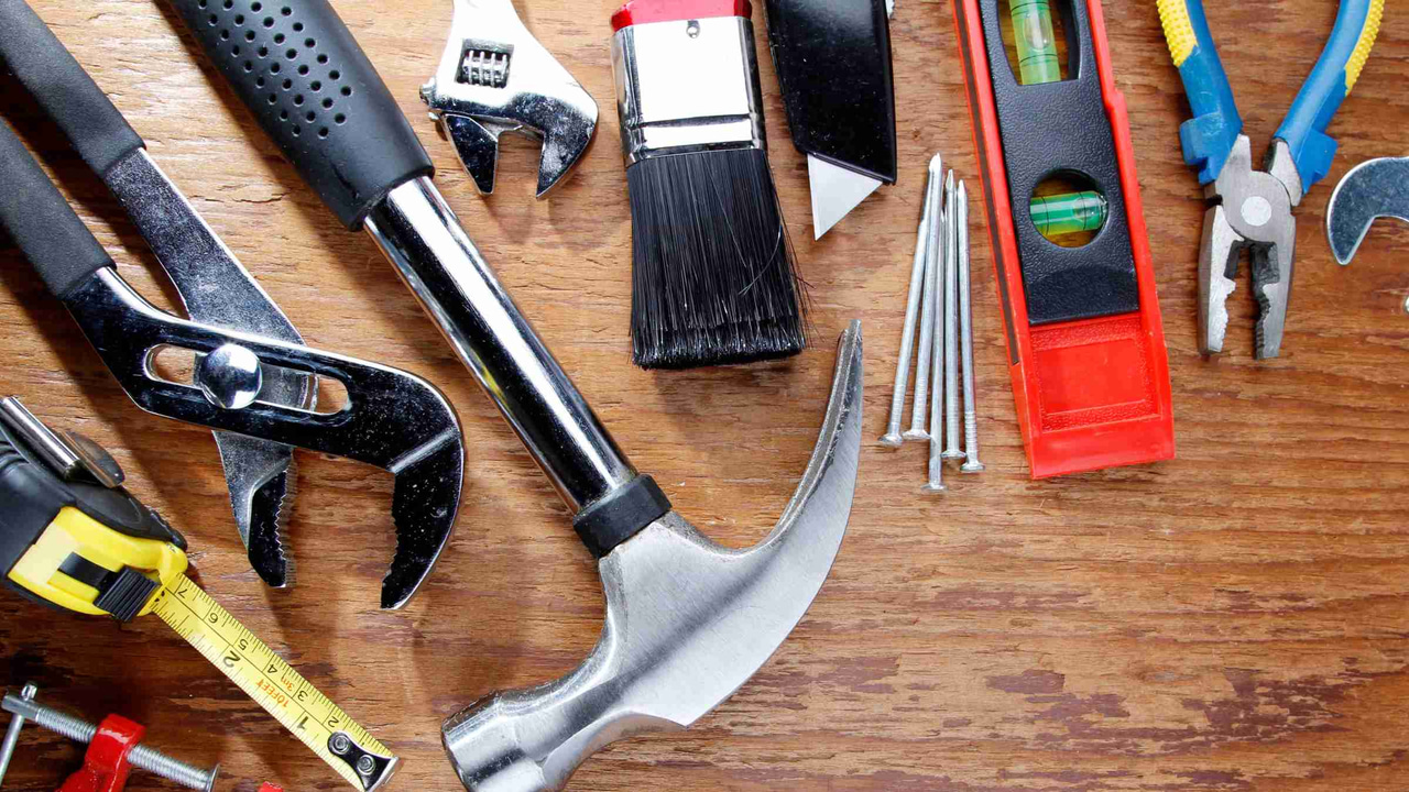 Row of tools on a table such as screwdrivers, wrenches, and a hammer